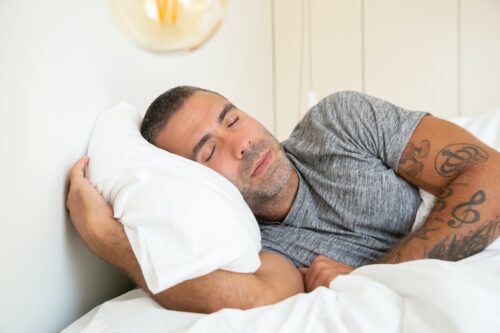 man sleeping with a white pillow
