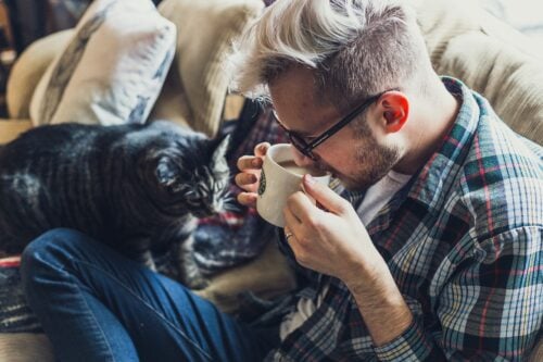 Man and his cat drinking coffee on sofa