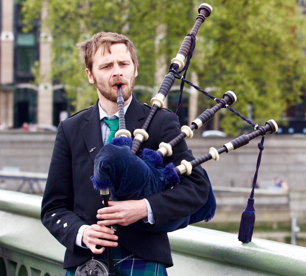 young man playing the bagpipes outside. Also used for funeral songs for dad and grandpa